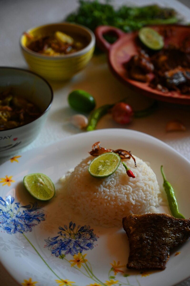 Delicious fish curry with rice, limes, and green chili served in Bangladesh.